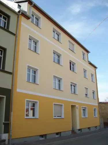 Mehrfamilienhaus mit gelber Fassade und mehreren Wohneinheiten