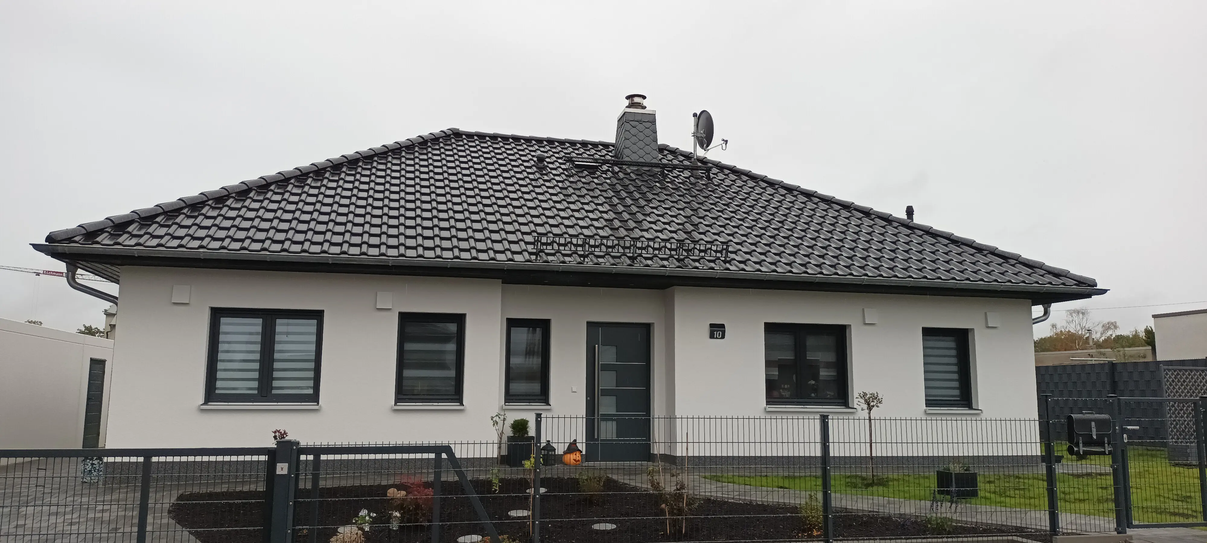 Moderner Bungalow in klarer, geradliniger Architektur mit heller Fassade, dunklem Walmdach und schlicht gestaltetem Vorgarten.