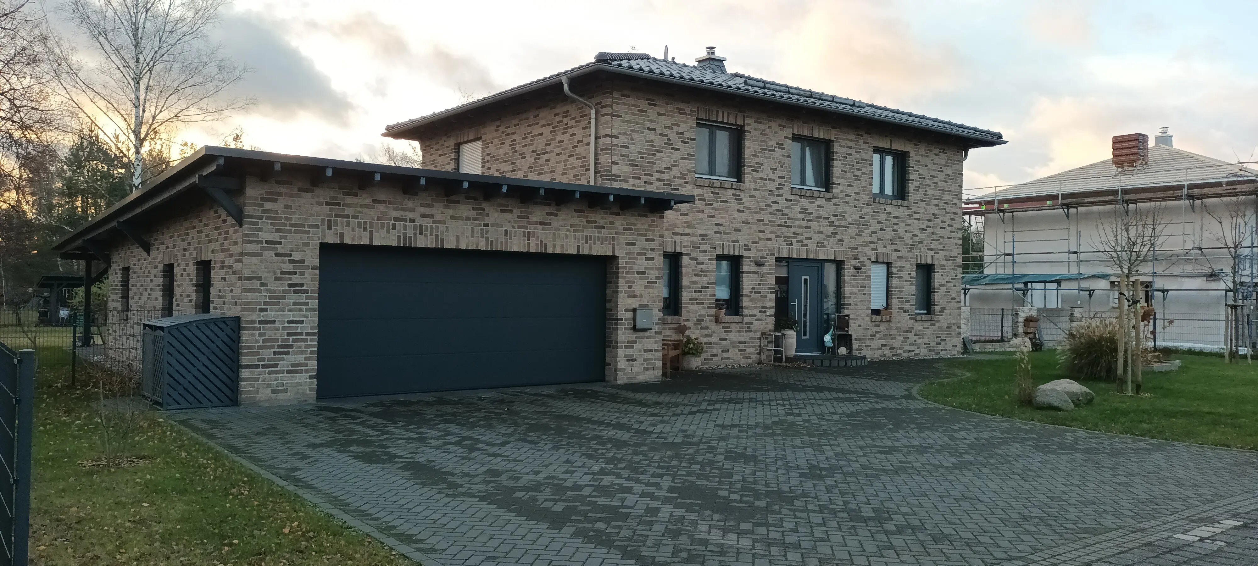 Großzügiges Einfamilienhaus mit Klinkerfassade, dunklem Dach und angebauter Garage in moderner, zeitloser Architektur.